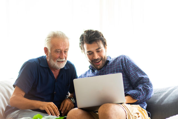 man helping senior father learn how to choose an independent living facility online