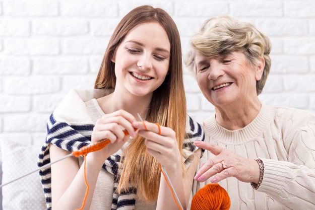 Passing her skills to next generations Close-up of a cheerful elderly woman teaching her granddaughter how to knit