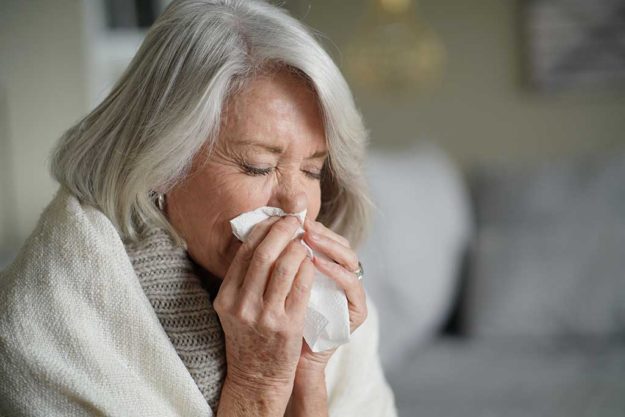 Senior woman blowing nose and feeling unwell Senior woman blowing nose and feeling unwell