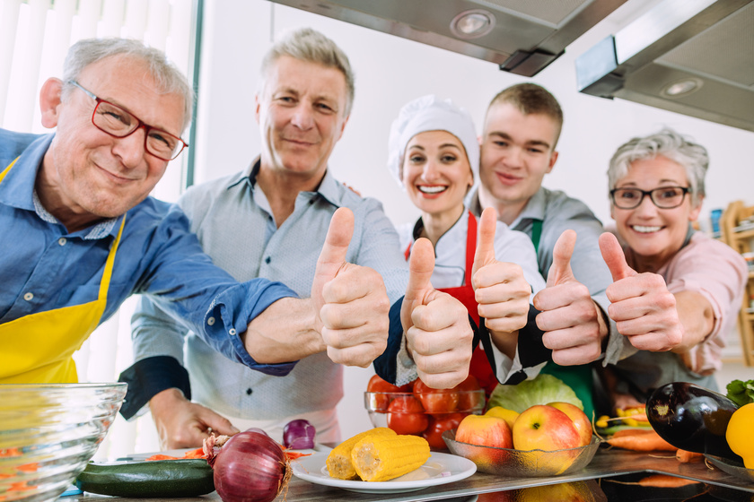 Trainees and their nutritionist in a training kitchen showing thumbs Trainees and their nutritionist in a training kitchen showing thumbs