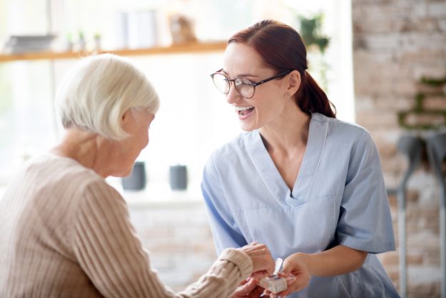Pleasant nurse laughing while speaking with retired lady Why Luxury Assisted Living In Florida Is So Popular
