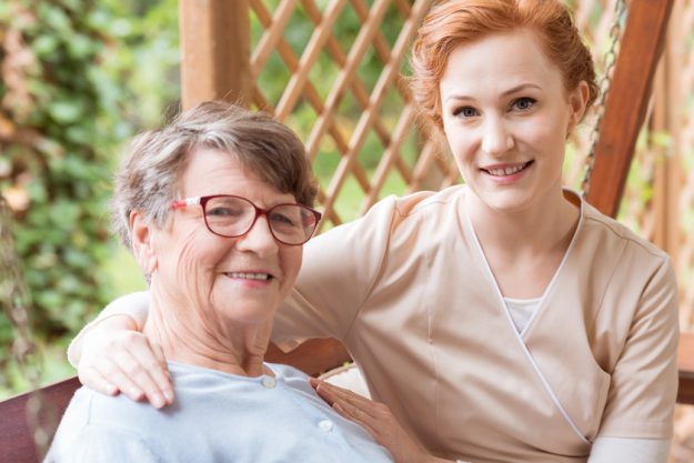 Close-up of a professional caregiver sitting next to and holding Understanding Luxury Assisted Living Trends In 2023