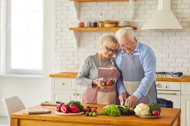 Mature married couple in aprons together prepare dinner Mature married couple in aprons together prepare dinner