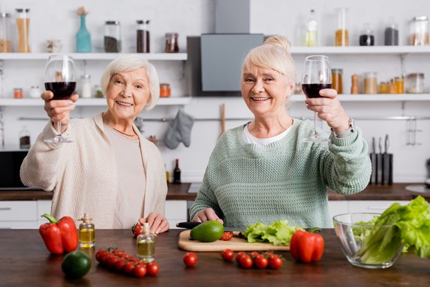 Happy senior women holding glasses of red wine Happy senior women holding glasses of red wine