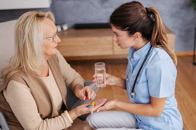 Blond senior woman sitting at home and holding hand Blond senior woman sitting at home and holding hand