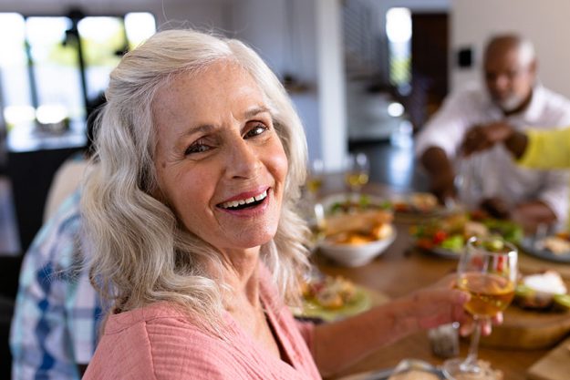 Portrait of senior multiracial woman enjoying wine while having lunch friends Portrait of senior multiracial woman enjoying wine while having lunch friends