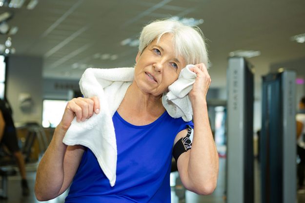 Senior female using towel after fitness training Senior female using towel after fitness training