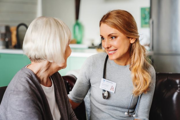 Caring nurse talking with old patient in living room at homecare visit. Medicine caregiving concept Caring nurse talking with old patient in living room at homecare visit. Medicine caregiving concept