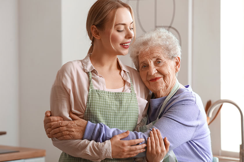 Young woman with her grandmother hugging in kitchen Young woman with her grandmother hugging in kitchen