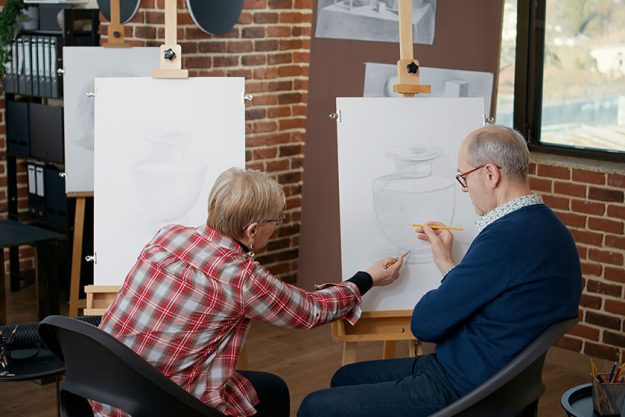 Senior man and woman at community centre drawing vase model Senior man and woman at community centre drawing vase model