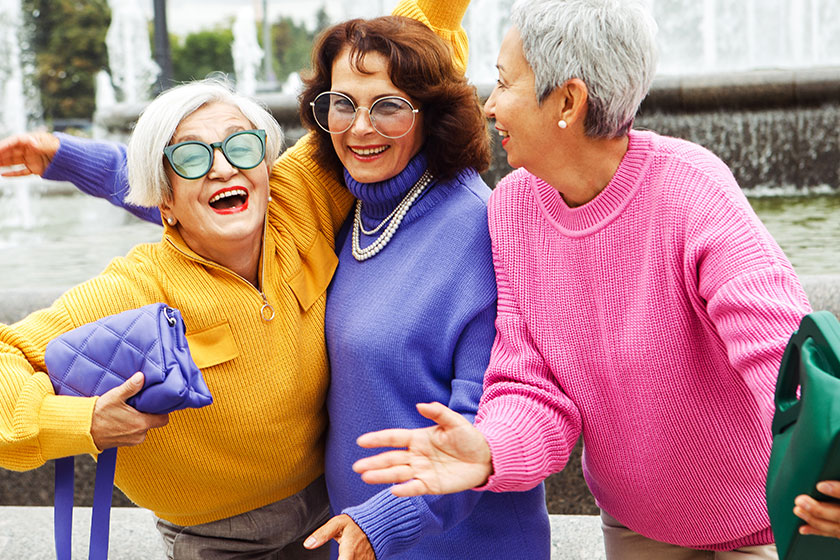 Three happy cheerful pensioner girlfriends in bright sweaters and sunglasses walk together in the city on an autumn day. Three happy cheerful pensioner girlfriends in bright sweaters and sunglasses walk together in the city on an autumn day.