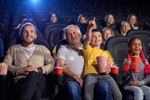 grandfather with grandson enjoying cartoon in cinema hall grandfather with grandson enjoying cartoon in cinema hall