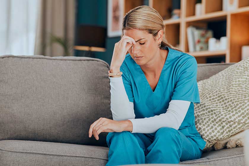 worry stress burnout woman nurse sitting sofa modern apartment home