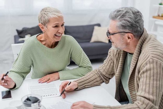 positive senior woman looking husband contract smartphone kitchen