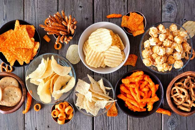 Assortment of salty snacks. Top view table scene on a dark Assortment of salty snacks. Top view table scene on a dark