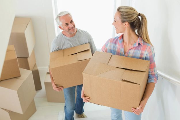 Happy couple carrying cardboard moving boxes Happy couple carrying cardboard moving boxes