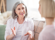 portrait of charming cheerful persons sit on sofa look each other