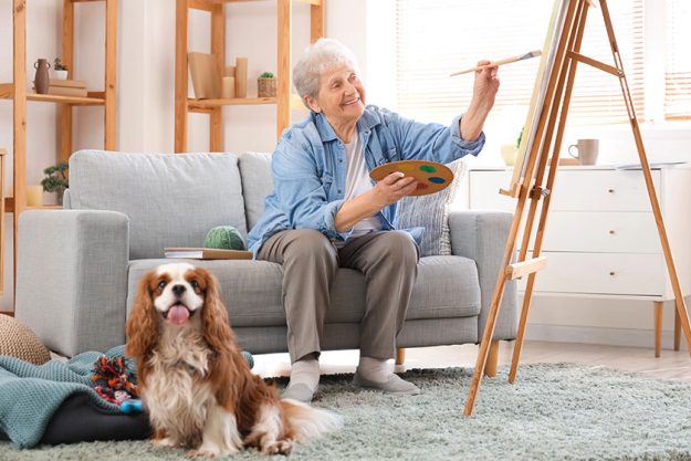 Senior woman cute cavalier king charles spaniel dog painting home Senior woman cute cavalier king charles spaniel dog painting home