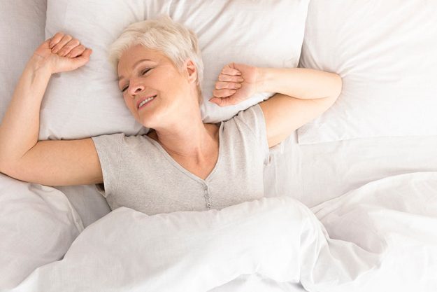 senior woman lying down in her bed at home senior woman lying down in her bed at home