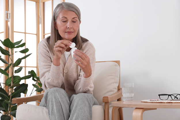 senior woman bottle pills armchair senior woman bottle pills armchair