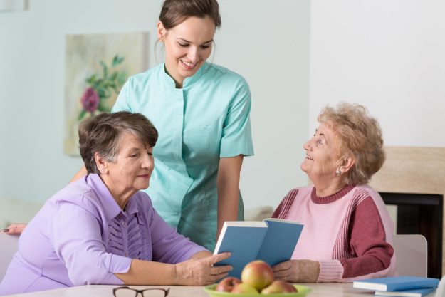 Two,Elder,Women,And,Young,Nurse,Reading,The,Book Two,Elder,Women,And,Young,Nurse,Reading,The,Book
