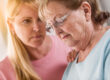 Young Adult Woman Consoles Sad Senior Adult Female.