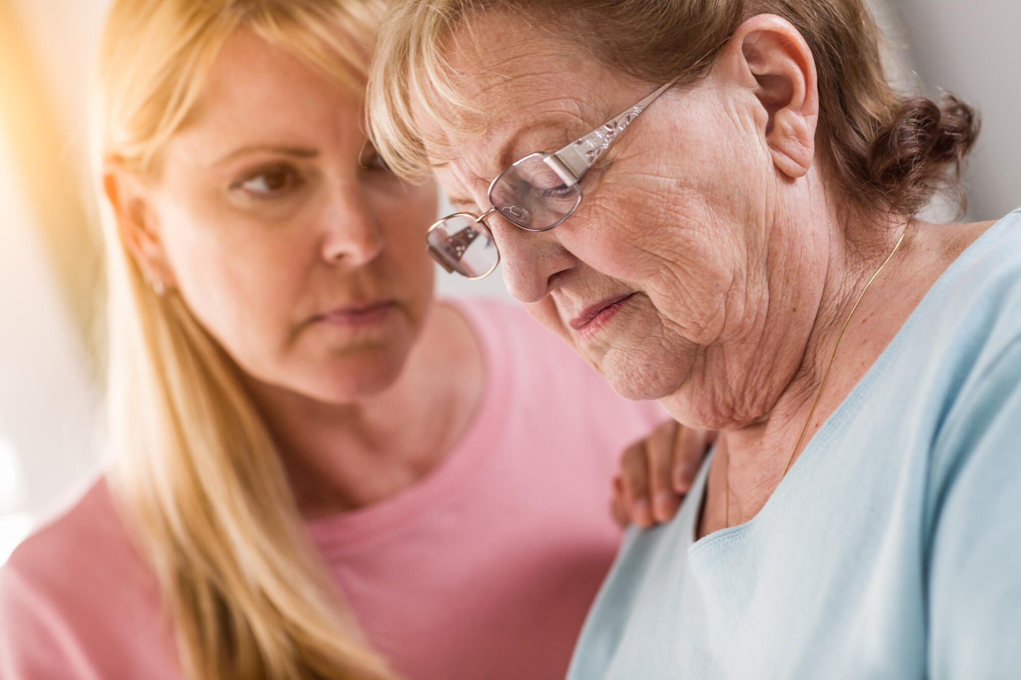 Young Adult Woman Consoles Sad Senior Adult Female. Young Adult Woman Consoles Sad Senior Adult Female.